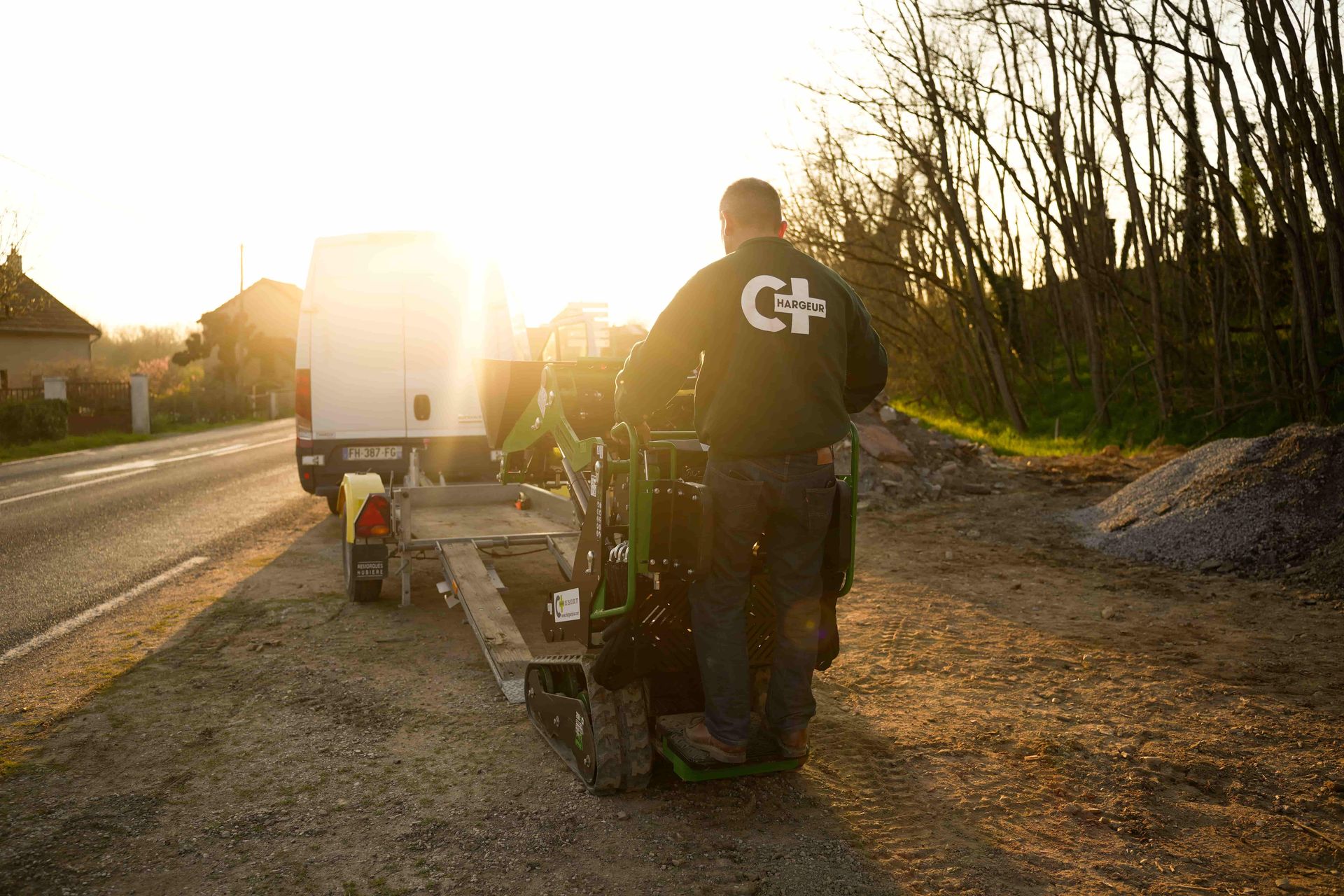 logo d'une mini-chargeuse en train d'être chargée sur une remorque