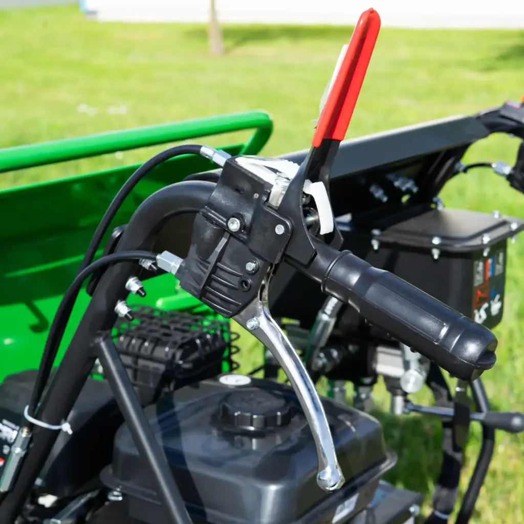 Gros plan sur la poignée droite et les commandes hydrauliques d’un mini dumper à chenilles, avec levier rouge de sécurité et réservoir visible en arrière-plan