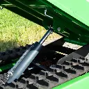 Zoom sur le vérin hydraulique de levage d’un mini dumper à chenilles, benne en position inclinée et chenilles visibles