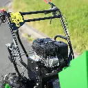Vue rapprochée du moteur et du guidon d’un mini dumper motorisé, avec commandes manuelles et pictogrammes de sécurité visibles