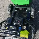 Vue de dessus du moteur, châssis et système de direction d’un mini dumper motorisé, avec benne verte relevée et pneus tout-terrain