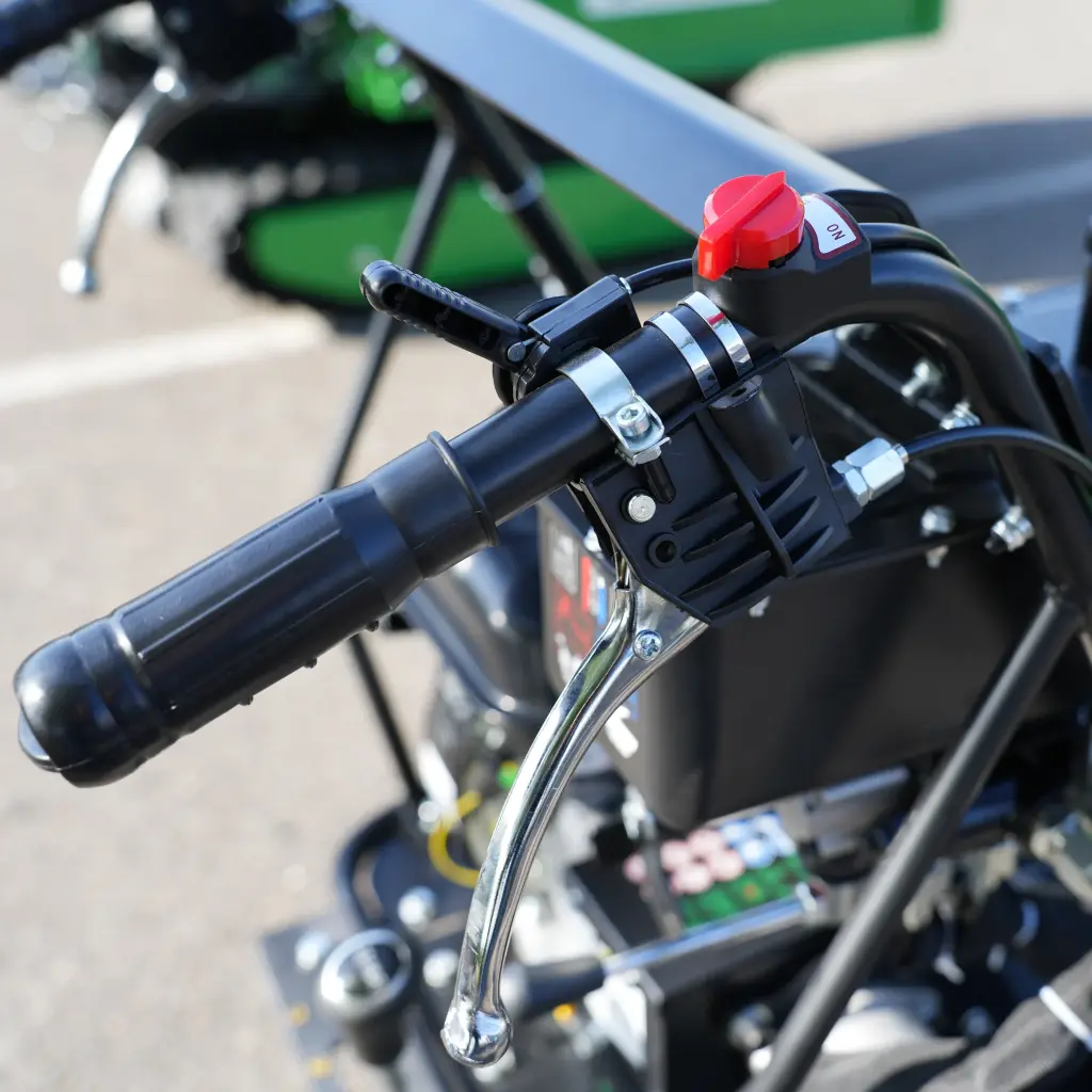 Poignée gauche d’un dumper Chargeur Plus avec interrupteur ON/OFF rouge, levier de frein et commande de sécurité intégrée