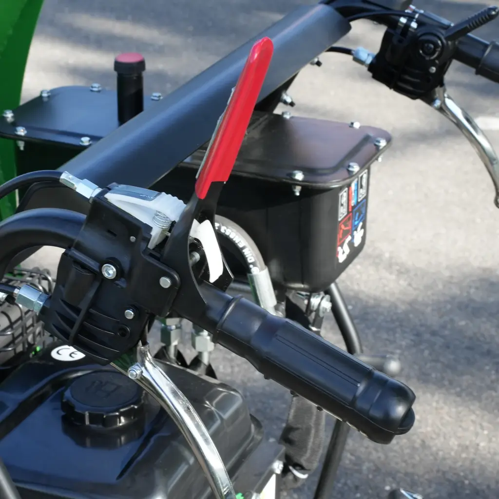 Commandes droites d’un dumper Chargeur Plus avec poignée ergonomique, levier de sécurité rouge et réservoir visible à l’arrière-plan