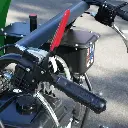 Commandes droites d’un dumper Chargeur Plus avec poignée ergonomique, levier de sécurité rouge et réservoir visible à l’arrière-plan