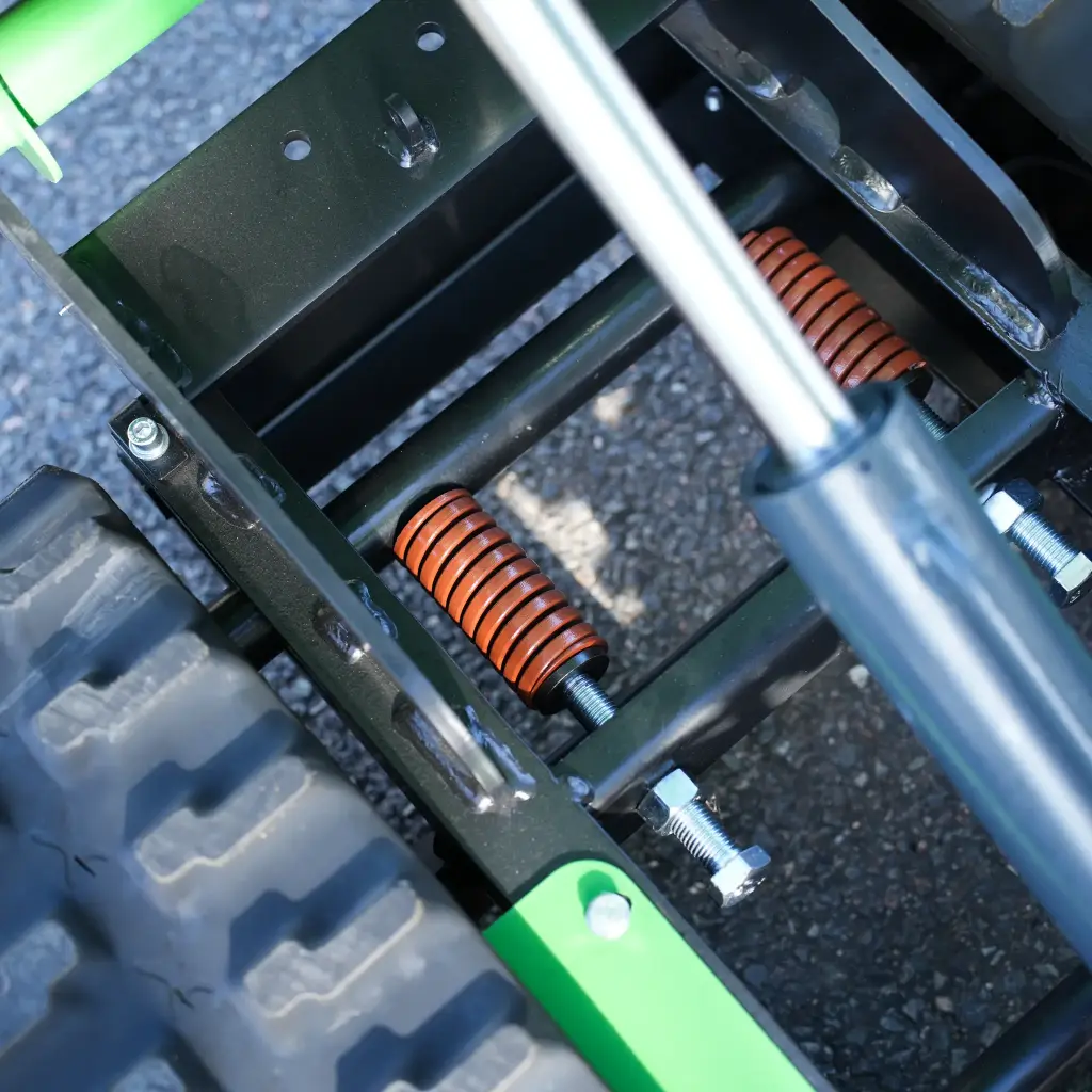 Système de suspension avec ressorts amortisseurs et vérin de levage d’un dumper Chargeur Plus à chenilles, vue rapprochée du châssis