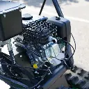 Gros plan sur le moteur thermique du dumper Chargeur Plus, avec échappement protégé par une grille, réservoirs et câblage visibles