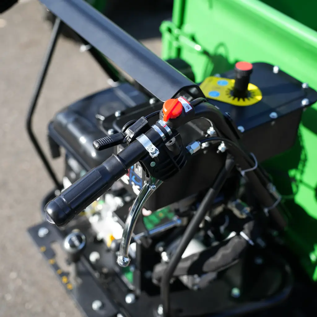 Poignée de commande du dumper Chargeur Plus avec interrupteur rouge ON/OFF, levier d’accélérateur et tableau de réglage en arrière-plan