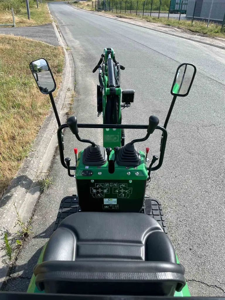 vue cabine en grand angle de la minipelle cp06 de chez chargeur plus sur une route goudronnée.webp