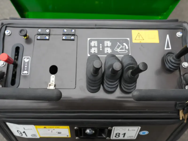 Tableau de commande d’un dumper à chenilles, avec leviers de contrôle, poignées de pilotage, schémas explicatifs et étiquettes de sécurité visibles.