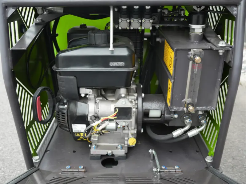 Compartiment moteur d’un dumper vert avec moteur thermique, réservoir hydraulique gradué, lanceur à rappel et composants mécaniques visibles.