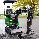 Chargeurplus vous présente la mini-pelle verte sur chenilles photographiée de face, bras hydraulique entièrement déployé vers l'avant avec le godet posé au sol, mettant en évidence la lame frontale, les chenilles en caoutchouc et l'ensemble de la mécanique hydraulique.