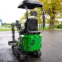 Chargeurplus vous présente la mini-pelle verte photographiée de l'arrière, mettant en valeur la carrosserie verte avec ses trappes d'accès, le bouton d'arrêt d'urgence rouge, le siège et la structure ROPS, avec le bras hydraulique et le godet visibles sur la gauche.