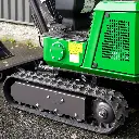Chargeurplus: Vue de trois quarts du train de chenilles, mettant en évidence la bande caoutchoutée renforcée, les galets de roulement et la conception robuste assurant stabilité et adhérence sur tous types de terrains.