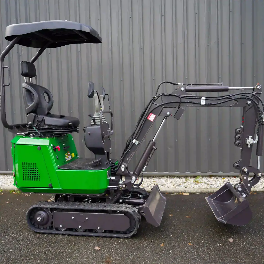 Chargeurplus vous présente la mini-pelle CP09 photographiée de profil gauche, offrant une vue complète du bras hydraulique articulé avec ses vérins, le godet, …Chargeurplus vous présente la mini-pelle CP09 photographiée de profil gauche, offrant une vue complète du bras hydraulique articulé avec ses vérins, le godet, la carrosserie verte, le siège avec accoudoirs et l'auvent de protection, devant un bardage métallique gris.