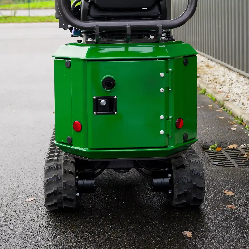 Chargeurplus vous présente un gros plan sur la partie arrière de la mini-pelle CP09, mettant en évidence la carrosserie verte avec sa trappe d'accès verrouillable, ses deux feux rouges, la prise de recharge et les chenilles en caoutchouc.