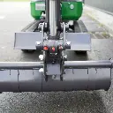 Chargeurplus vous présente un gros plan sur l'attache rapide de la CP09, montrant le système de verrouillage avec ses deux goupilles de sécurité rouges et oranges, ainsi que le godet cylindrique interchangeable monté en position basse.