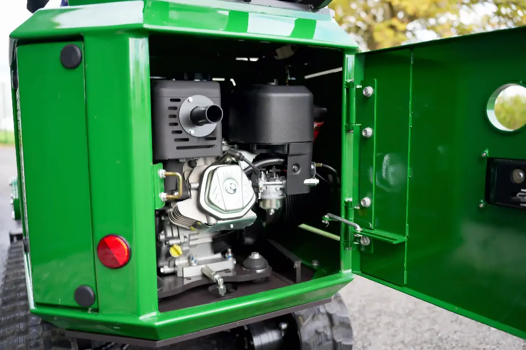 Chargeurplus vous présente un gros plan sur le compartiment moteur ouvert de la CP09, révélant le moteur thermique monocylindre avec son carburateur, son filtre à air et son échappement, logé dans un carter vert soigné avec trappe d'accès à charnières.