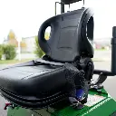 Chargeurplus vous présente un gros plan sur le siège opérateur de la CP09 vu de trois quarts, mettant en valeur l'assise en similicuir noir, le dossier ergonomique avec poignée de maintien et la ceinture de sécurité, sur fond de paysage extérieur flou.