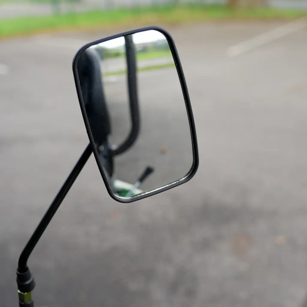 Chargeurplus vous présente un gros plan sur le rétroviseur rectangulaire de la CP09, monté sur tige métallique noire, reflétant l'environnement arrière et laissant entrevoir la carrosserie verte de la machine en bas du miroir.