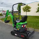 photo de derrière d'une mini-pelle CP12 avec sur un terrain, on aperçoit sur la photo les chenilles de la mini-pelle, les manettes, et un godet ou bout du bras de la flèche. Le vérin est inversé