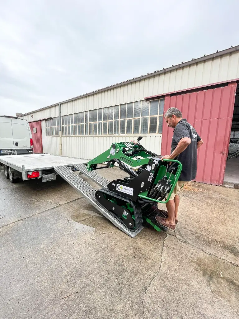 mini chargeuse mc306 de chez chargeur plus en cours de chargement par un client sur une remorque via des rampes.webp