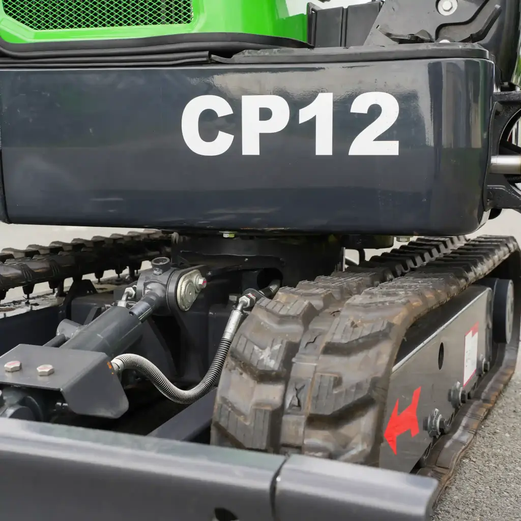 photo zoomé des chenilles de la mini-pelle de la gamme CP12 écrit en gros en blanc. Système de transmission visible