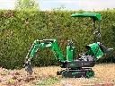 Vue de profil de la mini-pelle CP06 Chargeur Plus en intervention sur un chantier de dessouchage résidentiel.