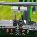 vue de haut et de face des manettes de commande de la mini-pelle. Boutons essence et batterie en rouge visibles.