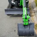 photo vue de haut du godet de la mini-pelle. Vérin inversé et lame visible. Chenilles et système de transmission visibles dans le fond, avec la gamme CP12 écrite en gros en blanc.