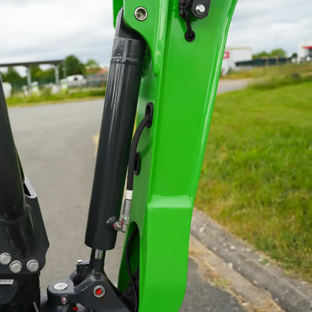 photo de côté des raccords hydrauliques et de la protection du vérin inversé visibles.
