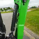 photo de côté des raccords hydrauliques et de la protection du vérin inversé visibles.